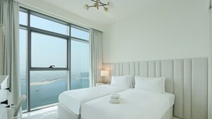 Ett hotellrum med två sängar, ett stort fönster med utsikt över staden, en modern kristallkrona och en inredning i vita nyanser.