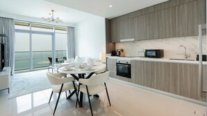 A modern kitchen with a built-in oven, microwave, and a large window overlooking a balcony. - Beachfront 2BR w Palm & Sea Views (Dubai)