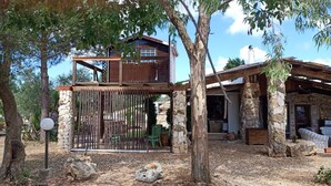 A rustic house with a stone exterior, a wooden upper level, and a covered porch.