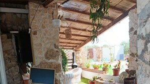 A stone-walled outdoor area with a rustic stone floor, a wooden barrel, and potted plants.