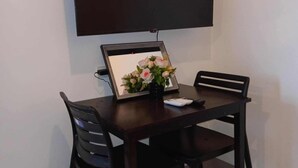 A dining area with a table and chairs, a framed picture, and a flat-screen TV mounted on the wall. - COAST RESIDENCE (Pasay)