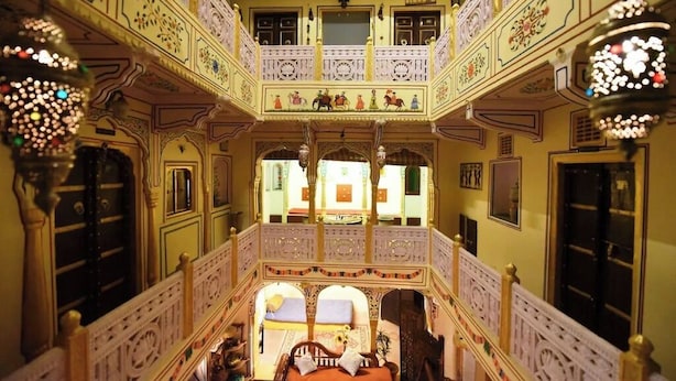 Un interior de varios niveles con balcones ornamentados, una zona de estar central y luminarias decorativas.
