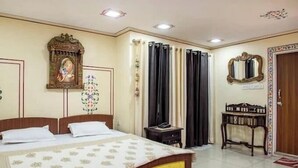 Una habitación de hotel con cama, mesita de noche, espejo y puerta con marco decorativo.