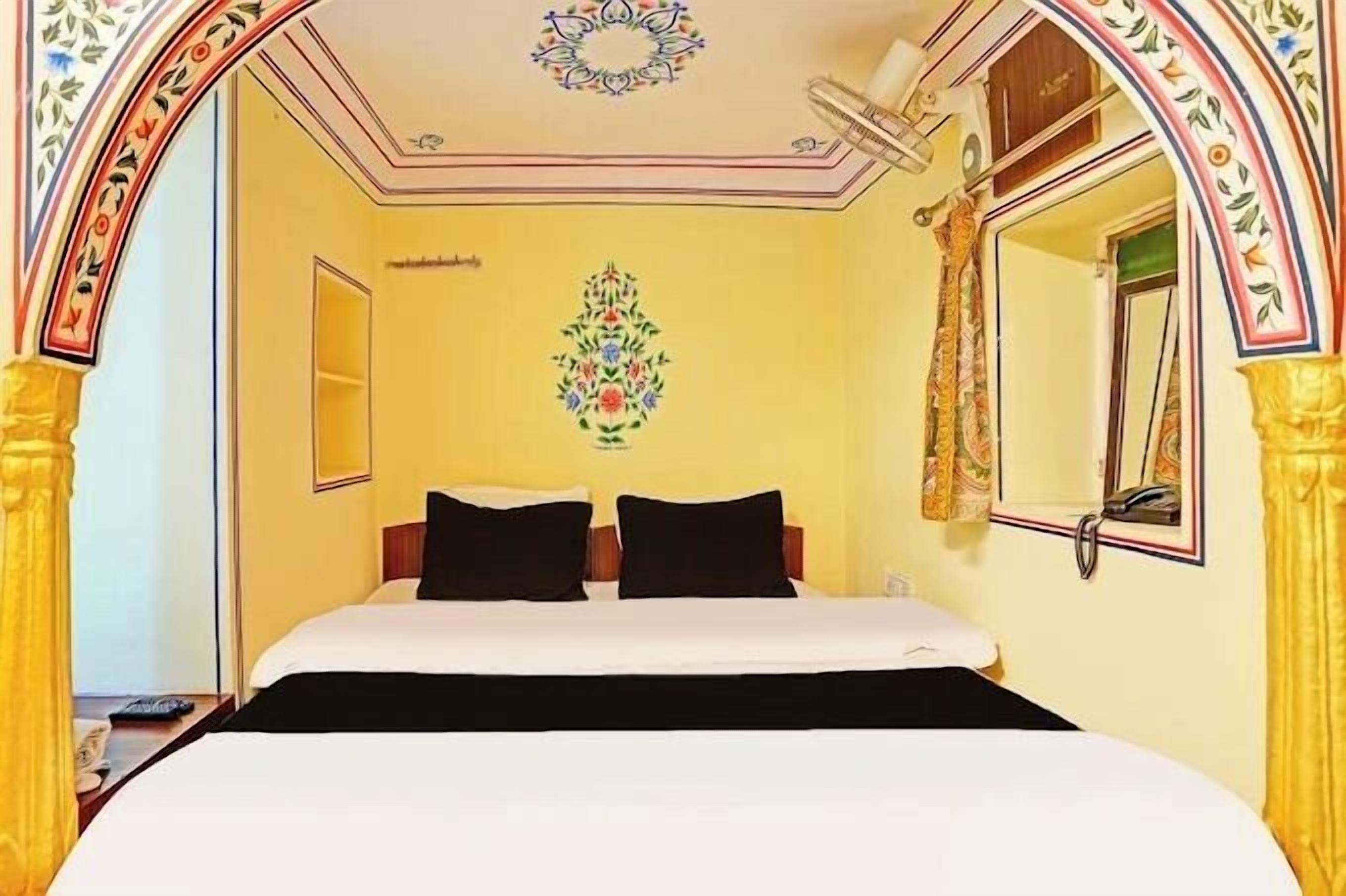 Una habitación de hotel con cama, espejo y un diseño decorativo en la pared.