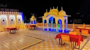 Un espacio exterior para comer con mesas y sillas, un arco decorativo y un suelo de baldosas.