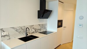 Una cuina moderna amb salabost amb acabats de marbre, un rentaplat i un microones integrat.