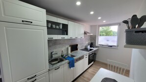 Een moderne keuken met witte kastjes, een inbouwoven, een spoelbak en een raam met uitzicht op groen.