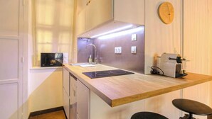 A compact kitchen with a wooden countertop, a built-in stove, and a wall-mounted clock. - Dify Apartment Ainay (Lyon)