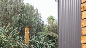 A pathway leading to a building with a corrugated metal exterior and a wooden post.