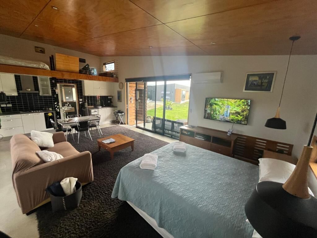 Een moderne hotelkamer met een bed, een slaapbank en een eethoek.