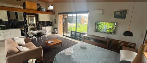 Een moderne hotelkamer met een bed, een slaapbank en een eethoek.
