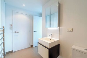 A modern bathroom with a white sink, a mirror above it, and a toilet. - Auckland CBD Brilliant Views 2 bedroom apartment (Auckland)