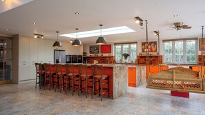 A spacious kitchen with a central island, bar stools, pendant lighting, and a ceiling fan.