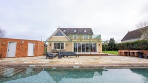 Una casa de dos pisos con una piscina al frente.