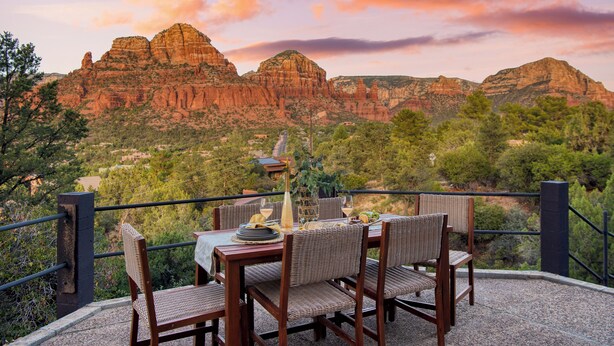 A dining table set with chairs and a view of red rock formations.