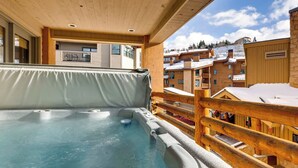 A hot tub area with a wooden deck and a view of snow-covered buildings. - 7 Condos, Ski-in/Ski-Out + Hot Tubs | Sleeps 30 | Mont Cervin by AvantStay (Park City)