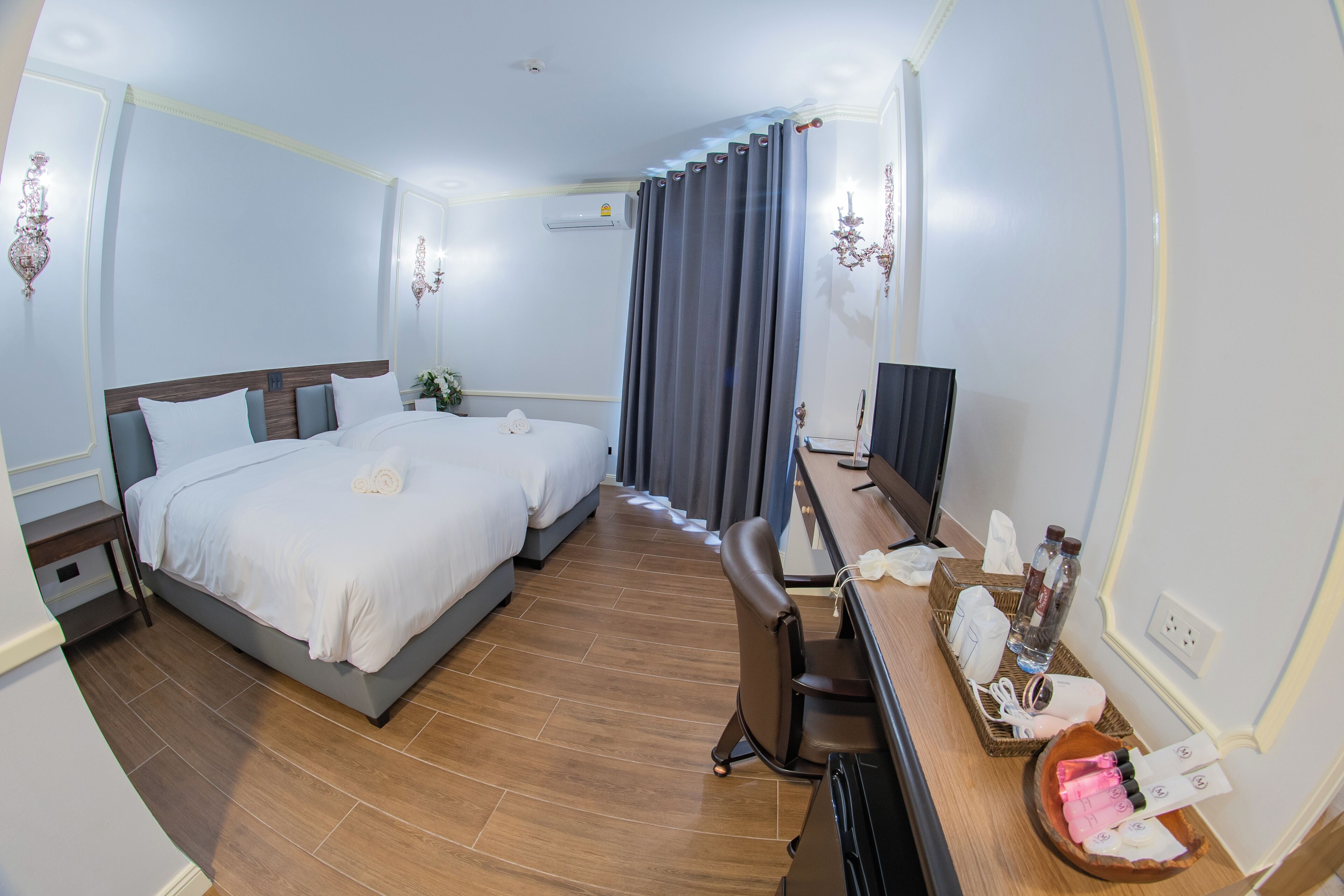 A hotel room with a bed, desk, chair, and a TV.