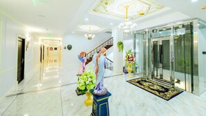 A hotel lobby with marble flooring, a grand staircase, and decorative statues. - The MACEO Hotel (Nong Khai)