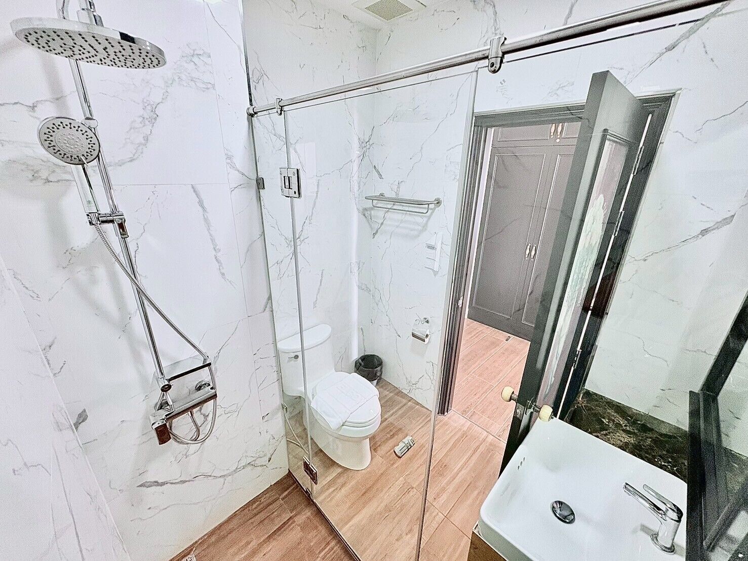 A bathroom with a glass-enclosed shower, a toilet, and a sink.