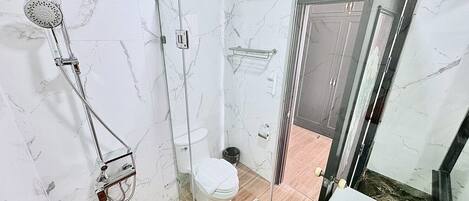 A bathroom with a glass-enclosed shower, a toilet, and a sink.