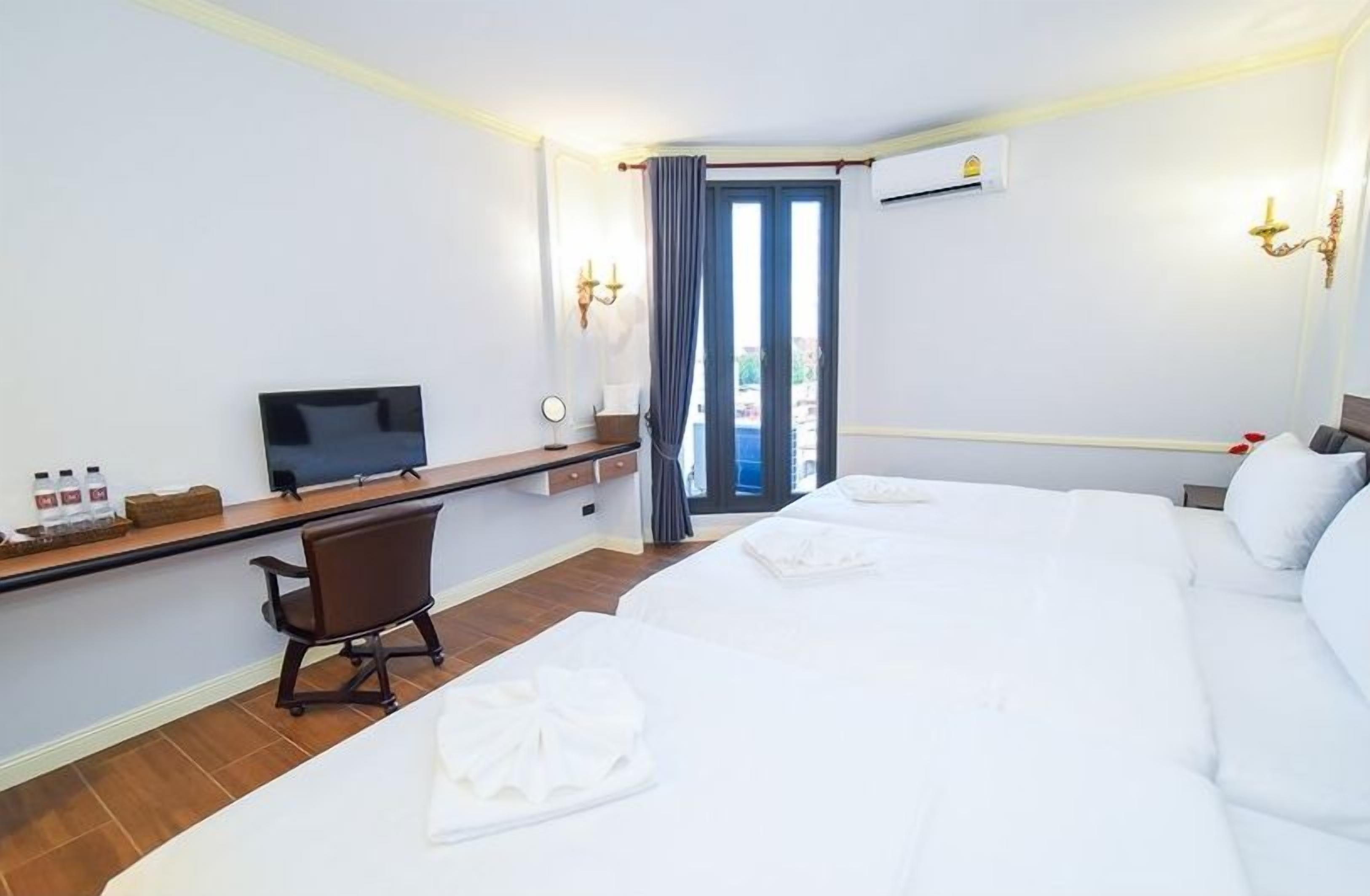 A hotel room with a bed, a desk, a chair, a television, and a window with curtains.