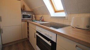 A compact kitchen with a microwave, stove, oven, and a skylight. - Moin Moin 2 Am Kampland - "Moin Moin 2" ... Welcome! (Dahme)