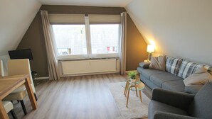 A modern living room with a dining area, a grey sofa, a small coffee table, and a radiator. - Moin Moin 2 Am Kampland - "Moin Moin 2" ... Welcome! (Dahme)