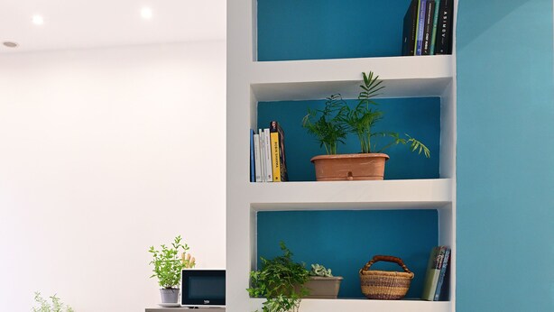 A modern kitchen with a built-in bookshelf, a sink, and a laptop on the countertop. - At Home Montebello (Rome)