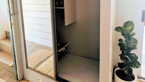 Una habitación con una puerta corrediza de vidrio que da a un balcón, una planta en maceta y suelo de baldosas.