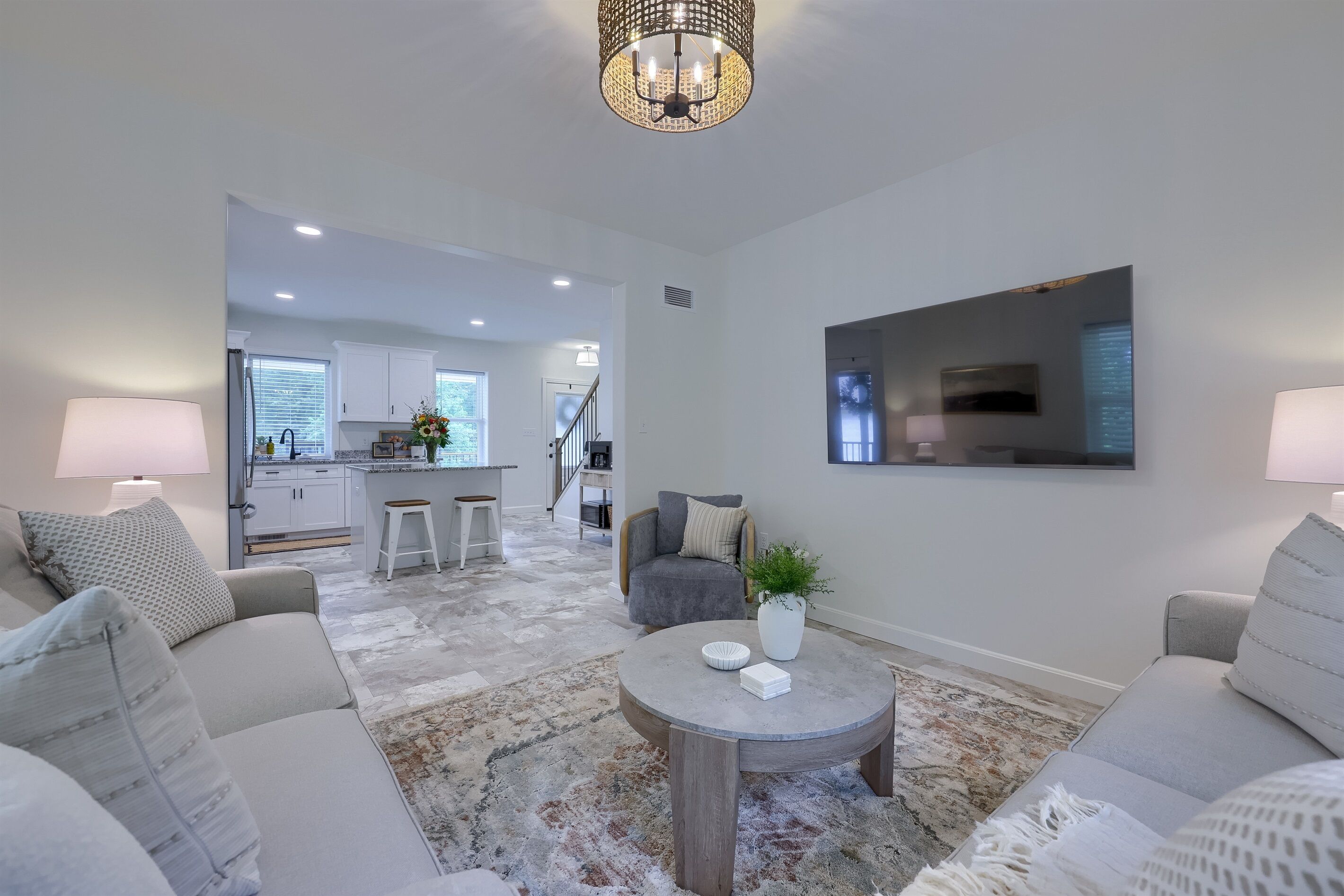 A modern living room with a round coffee table, two sofas, and a chandelier.