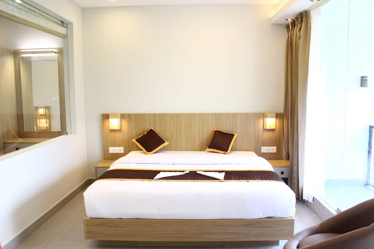 A hotel room with a large bed, two bedside tables, a mirror, and a window with curtains.