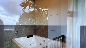 Ein modernes Badezimmer mit einer großen Badewanne, einer Duschkabine aus Glas und Blick ins Freie.