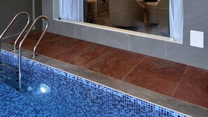 Ein modernes Hotelzimmer mit großem Fenster, einem Badezimmer mit Dusche und einem Poolbereich.