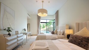 A modern hotel room with a large bed, a bedside table, a dresser, and a view of the outdoors. - Silk Valley - 4B  private beach access (Ghantoot)