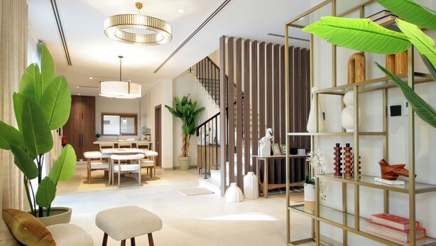 A modern living room with a staircase, a dining area, and a bookshelf. - Silk Valley - 4B  private beach access (Ghantoot)