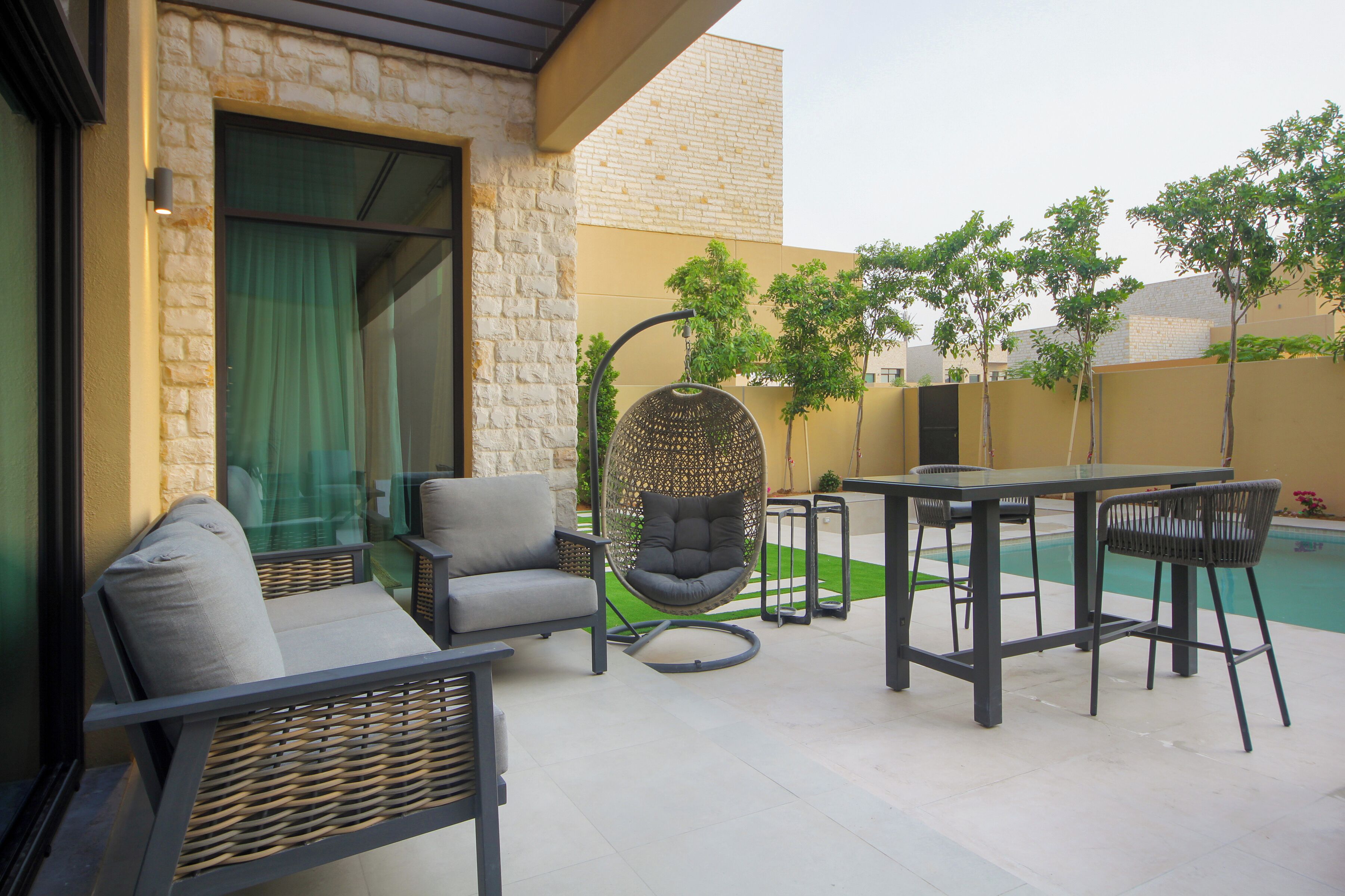 Eine Terrasse im Freien mit Esstisch, Stühlen, einer Hängematte und einem kleinen Pool.
