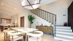 A modern kitchen with a dining area, featuring a white table, chairs, and a staircase with a railing. - Silk Valley - 4B  private beach access (Ghantoot)