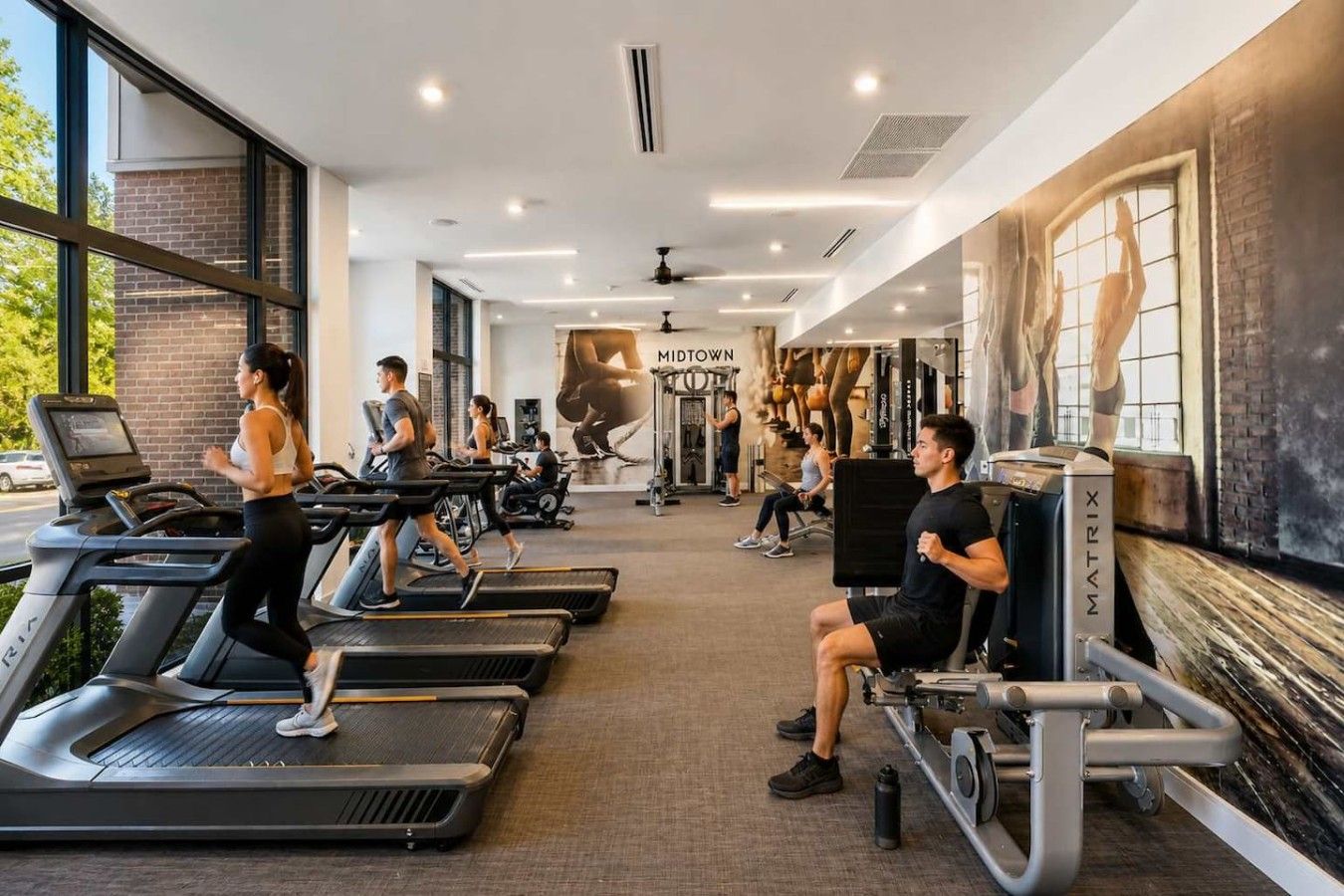 Een sportschool met loopbanden, krachtapparaten en een muurschildering.