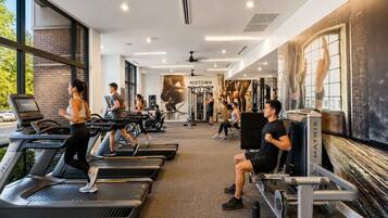 Een sportschool met loopbanden, krachtapparaten en een muurschildering.