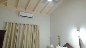 A room with a ceiling fan, an air conditioning unit, and a curtain.