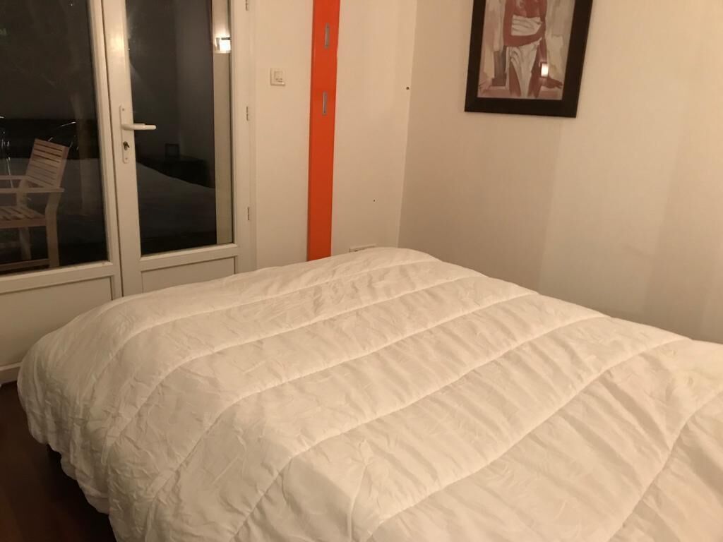 A bedroom with a white bedspread, a sliding glass door, and a framed picture on the wall.