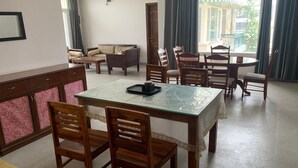 A dining area with a glass-top table, wooden chairs, and a bench in the background. - IT City Homestay-Secure & Comfortable Stay in Mohali (Sahibzada Ajit Singh Nagar)