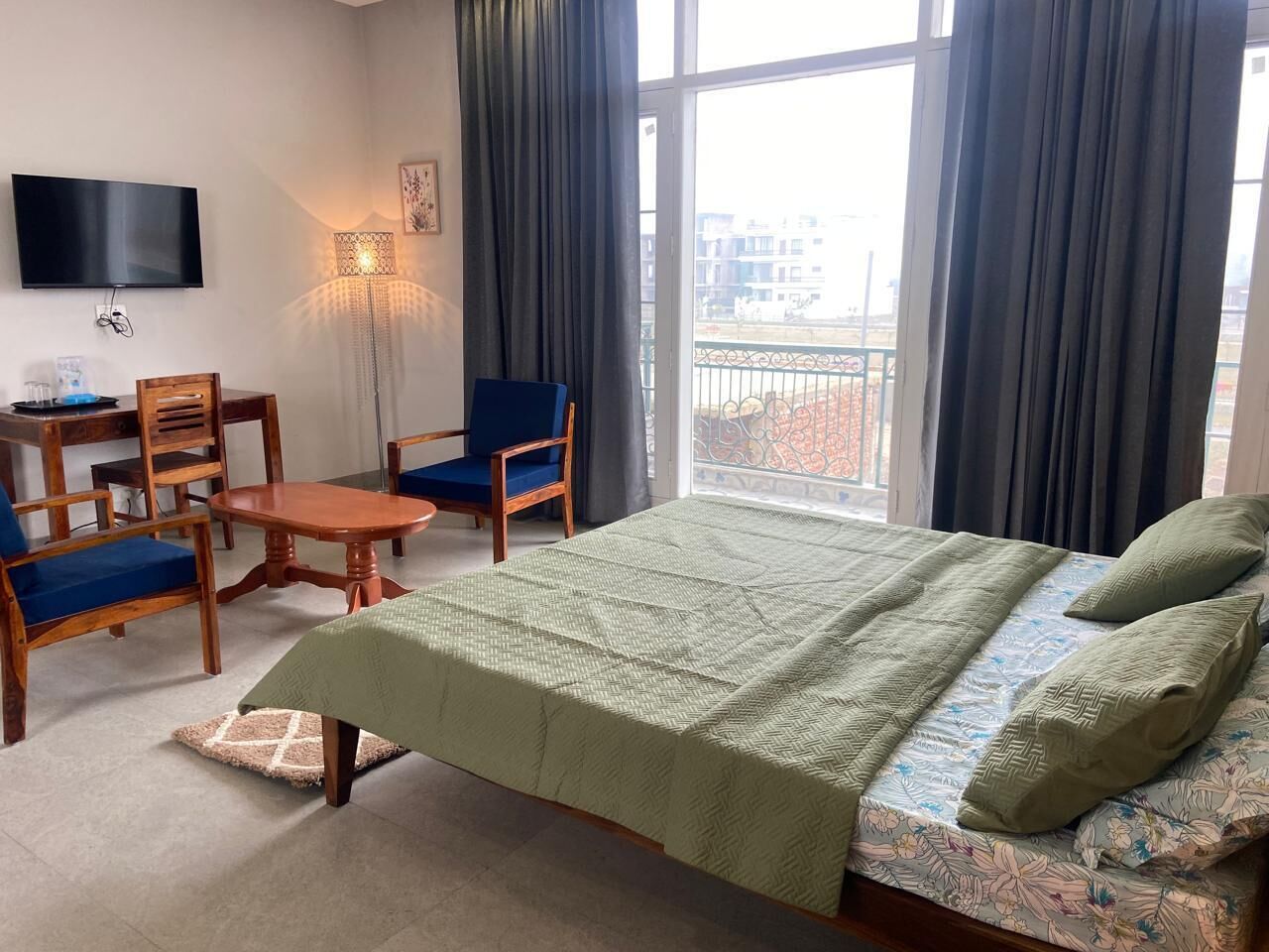 Habitación de hotel con cama, escritorio, silla, televisor y ventana con cortinas.