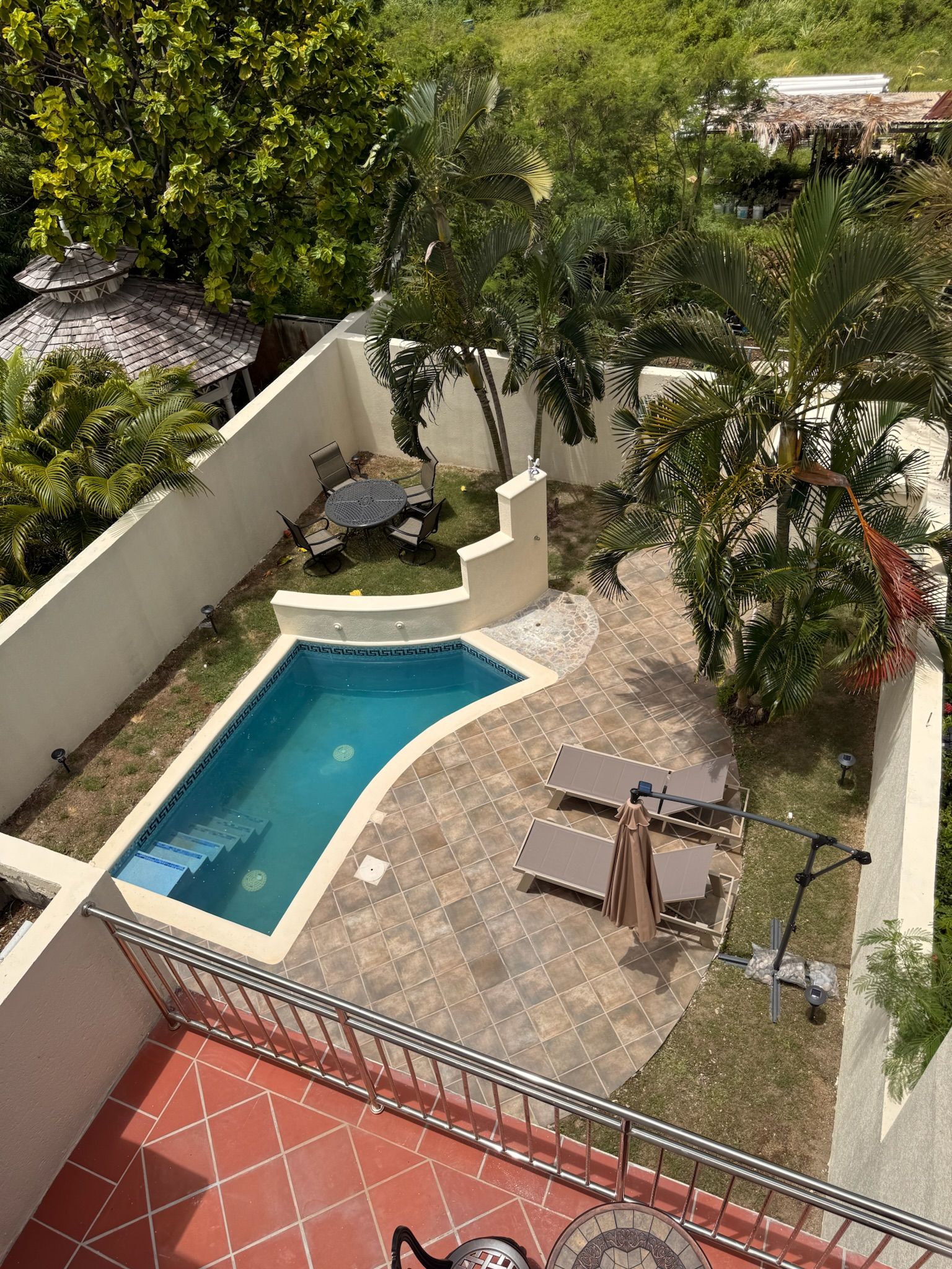 A rooftop pool area with a small pool, lounge chairs, and a pergola.