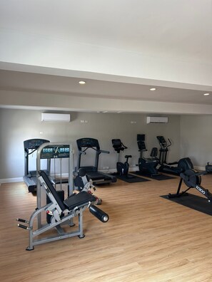 Un gimnasio con equipos de ejercicio variados, incluyendo cintas de correr, elípticas y máquinas de pesas.