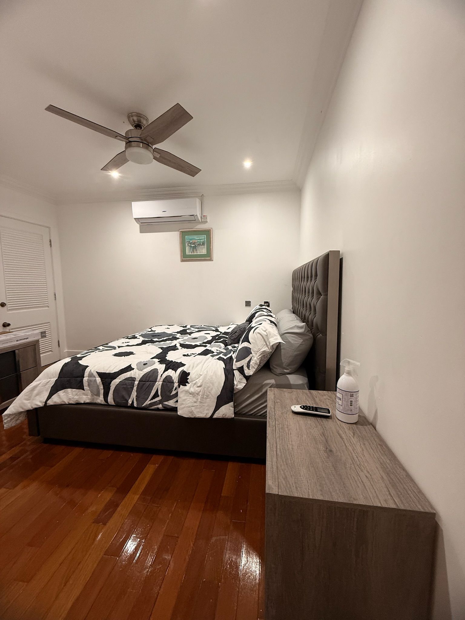 Una camera da letto con un letto, un comodino, un telecomando e una ventola a soffitto.