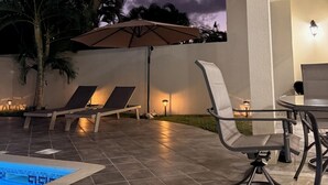An outdoor patio area with a swimming pool, lounge chairs, and a table. - Villa Ray: 3BR Gated Gem with Private Pool, Steps to Beach (Gros Islet)