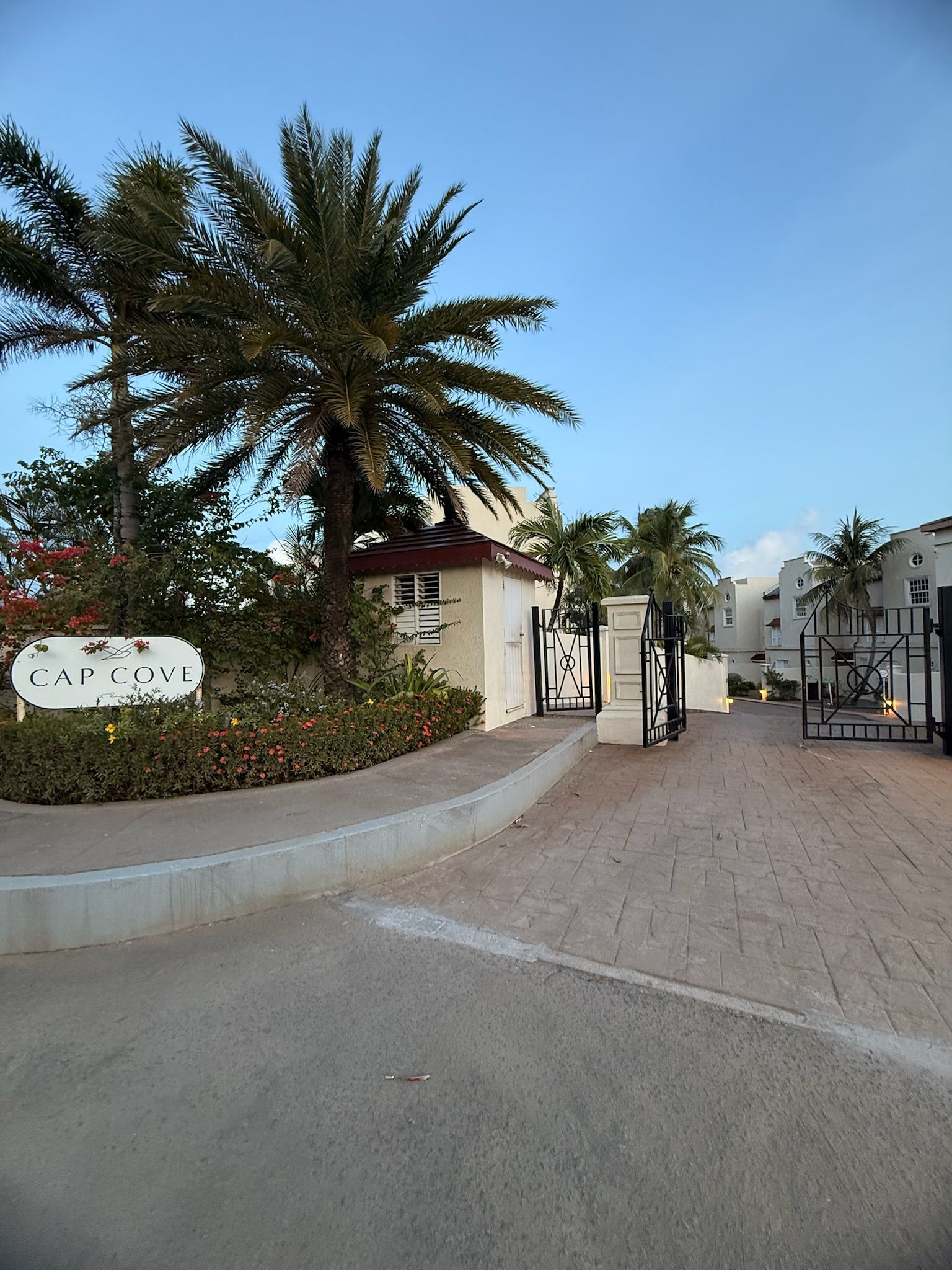 Una entrada cerrada a una zona residencial con palmeras y un cartel que dice 'CAP COVE'.
