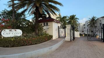 Una entrada cerrada a una zona residencial con palmeras y un cartel que dice 'CAP COVE'.