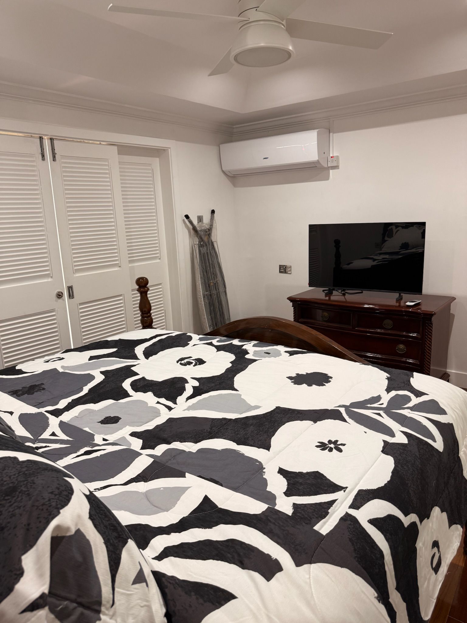 Un dormitorio con cama, cómoda, televisor y equipo de aire acondicionado.